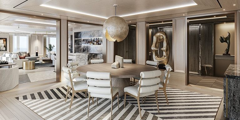 A luxury cruise suite living and dining room with a round table and sculptures