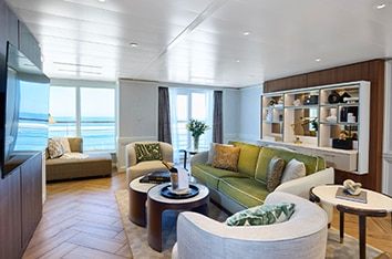 A suite sitting room with sofas and floor-to-ceiling ocean-view windows