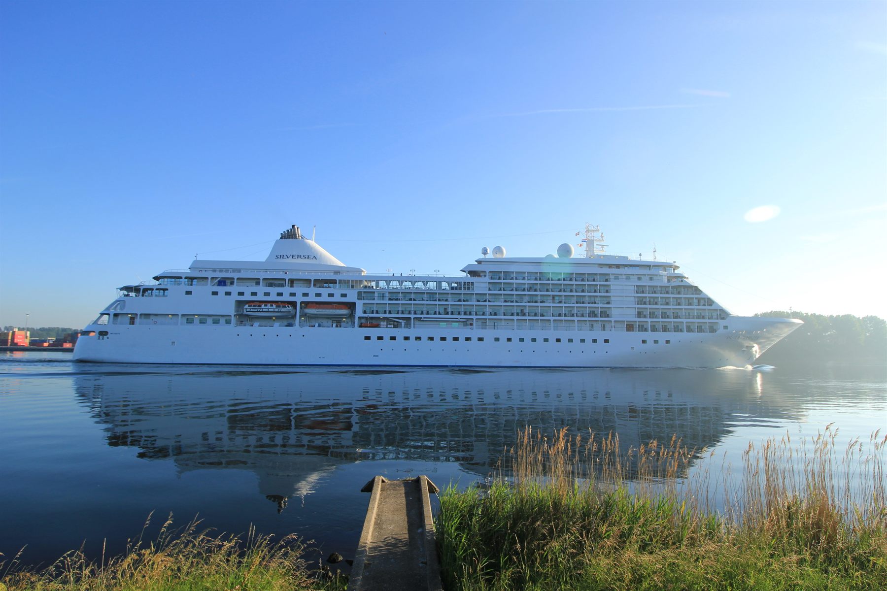 Silversea’s Silver Whisper sailing along a calm, reed-lined canal